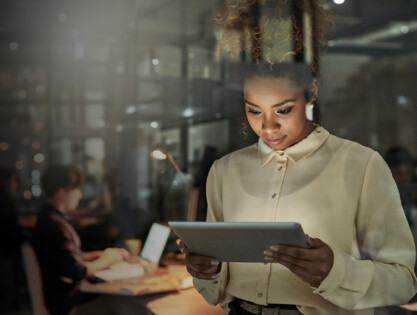 Shot of an attractive young designer working late at the office with her colleagues in the background
