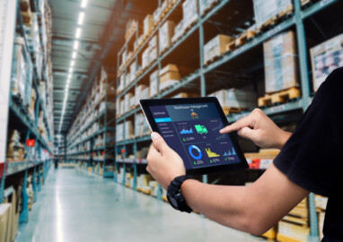 Worker hands holding tablet on blurred warehouse as background