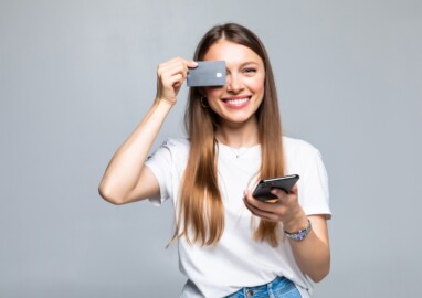 Cheerful excited young woman with mobile phone and credit card
