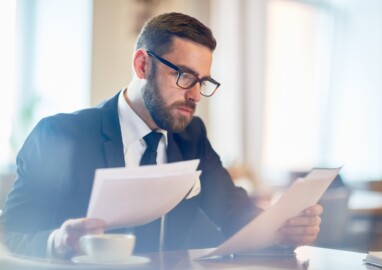 Confident banker reading financial papers while sitting in cafe