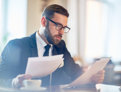 Confident banker reading financial papers while sitting in cafe
