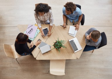 view-from-above-of-group-young-professional-entrepreneurs-sitting-at-table-in-coworking-space-discussing-profits-of-last-team-project-using-laptop-digital-tablet-and-smartphone